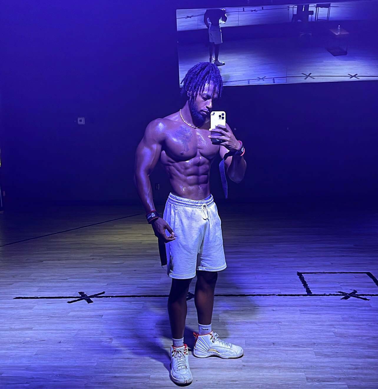 Coach taking photo infront of mirror showing his abs.